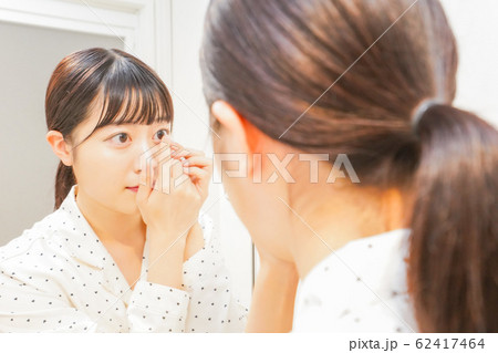 コンタクトレンズを装着する若い女性 コンタクトレンズを装着する若い女性 62417464