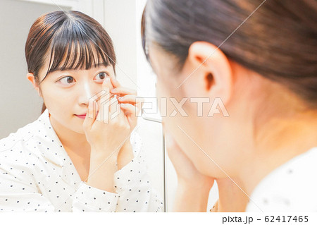 コンタクトレンズを装着する若い女性 62417465