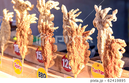 Large fried Japanese squid fried on skewers for sale in street food in Thailand. Large fried Japanese squid fried on skewers for sale in street food in Thailand. 62419895