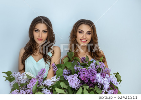Studio fashion portrait photo of two twins women with a bouquet of spring flowers 62421511