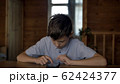 funny boy sits at a table at home and uses a phone, plays game 62424377