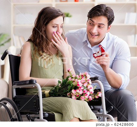 Man making marriage proposal to disabled woman on wheelchair Man making marriage proposal to disabled woman on wheelchair 62428600