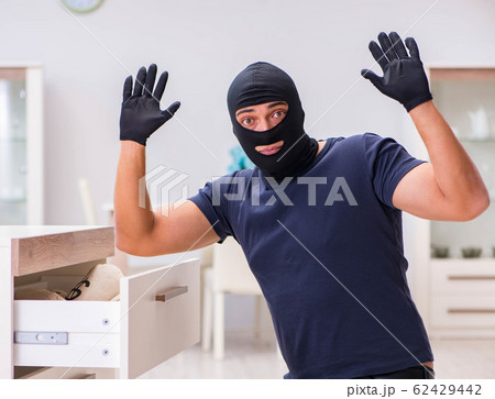 Robber wearing balaclava stealing valuable things 62429442