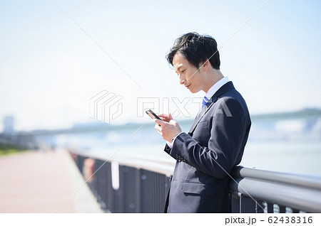 外でスマホを持つビジネスマン 外でスマホを持つビジネスマン 62438316