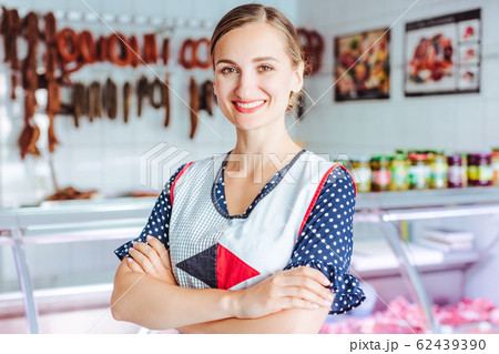 Proud woman selling meat and sausages in butcher shop 62439390