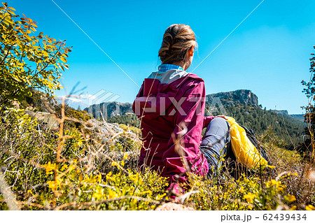 Woman having rest from hiking watching the hills and nature in spring Woman having rest from hiking watching the hills and nature in spring 62439434