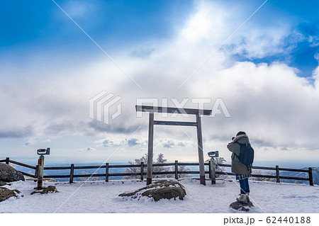 三重県　冬の御在所山頂　樹氷の山頂　鳥居越しに写真を撮る女性 62440188