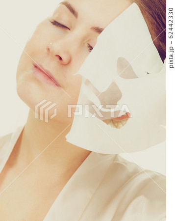 Woman removing sheet mask from face Woman removing sheet mask from face 62442330