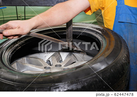 The master removes the tire from the cars drive The master removes the tire from the cars drive 62447478