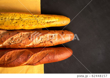 Three crispy french baguettes lie on an old wooden 62448157
