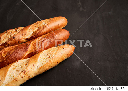Three crispy french baguettes lie on an old wooden 62448185