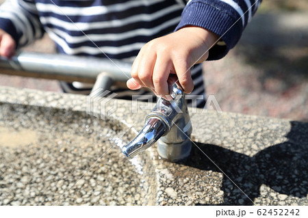 水道の蛇口に手をかける子供の写真素材