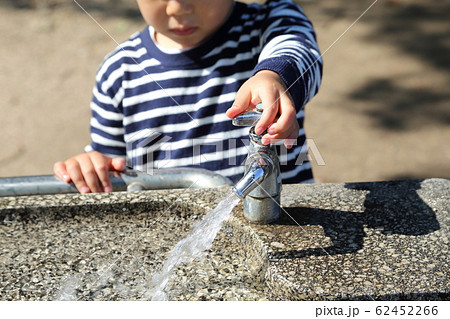 水道の蛇口に手をかける子供の写真素材