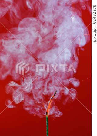 Burning fuse wick cord with sparks and smoke on red background Burning fuse wick cord with sparks and smoke on red background 62452879