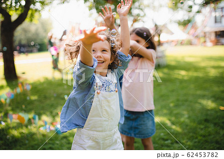 Small children standing outdoors in garden in summer, playing. Small children standing outdoors in garden in summer, playing. 62453782