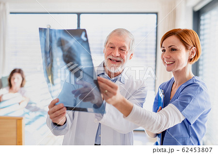 Doctors standing in hospital room, examining an X-ray. 62453807