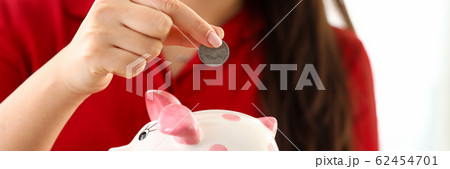 Female hand putting silver quarter into funny piggybank slot 62454701