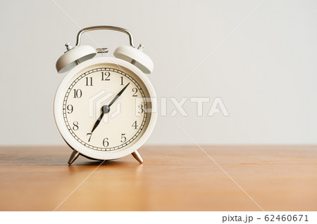 White alarm clock on brown wood desk and cream 62460671