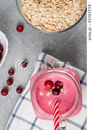 Freshly homemade smoothie with cranberries, oatmeal and yogurt in a mug jar on a gray table. Healthy eating concept. Vertical image, top view, flatlay 62463558