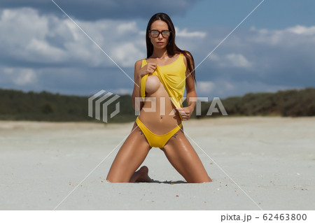 Sensual woman kneeling on beach Sensual woman kneeling on beach 62463800