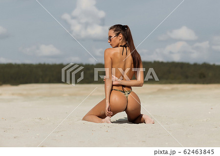 Seductive lady doing hair on beach 62463845