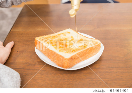 食パンにシロップを掛ける女性 62465404