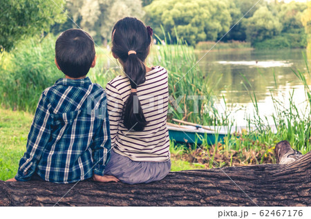 Two children, boy and girl, sitting on trunk of 62467176