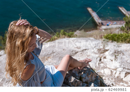 A young woman in a summer dress sits on the edge A young woman in a summer dress sits on the edge 62469981