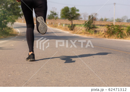 Close up Athlete running woman wearing Exercise pants and running shoe on the road,Runner woman traning in the morning.Walking for warm up her muscle. Close up Athlete running woman wearing Exercise pants and running shoe on the road,Runner woman traning in the morning.Walking for warm up her muscle. 62471312