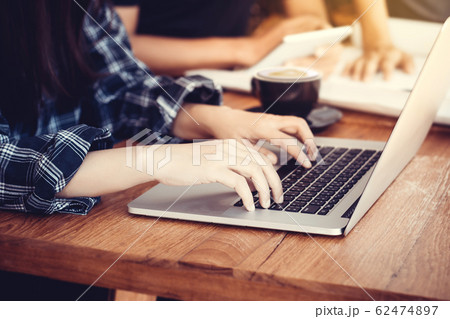 Businesswoman sitting at office desk and typing on a laptop hands close up , anonymous face 62474897