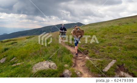 Tourists with hiking backpacks walk along a Tourists with hiking backpacks walk along a 62479399