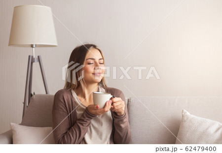 Millennial woman enjoying smell of fresh coffee at home Millennial woman enjoying smell of fresh coffee at home 62479400