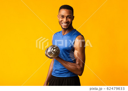 African bodybuilder pumping up dumbbells at orange studio African bodybuilder pumping up dumbbells at orange studio 62479633