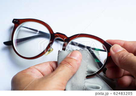 Woman's hands cleaning shortsighted or nearsighted eyeglasses by microfibre cleaning cloths, On white background, Close up & Macro shot, Selective focus, Optical concept Woman's hands cleaning shortsighted or nearsighted eyeglasses by microfibre cleaning cloths, On white background, Close up & Macro shot, Selective focus, Optical concept 62483205