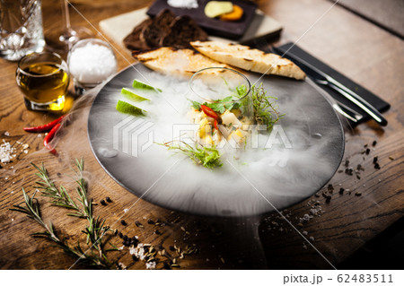 Scallop ceviche served in black bowl with liquid ice smoke 62483511