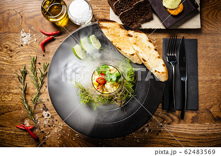 Scallop ceviche served in black bowl with liquid ice smoke 62483569