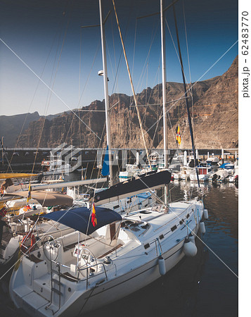 Toned image of expensive yachts moored in port against high cliffs and mountains Toned image of expensive yachts moored in port against high cliffs and mountains 62483770