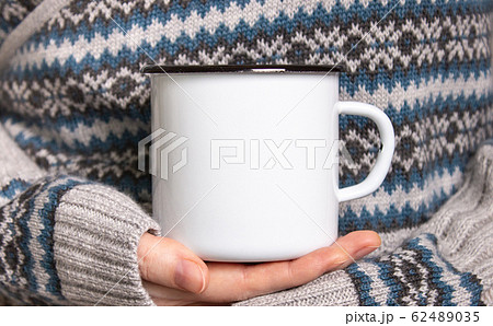 Enamel Mug with black edge line Mock-up. Girl holds white old-tin campfire cup in her hands 62489035