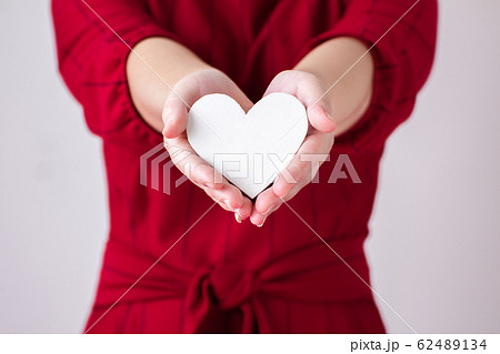 White Paper heart is being filed by woman hand. 62489134