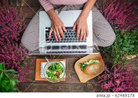 Top view of senior woman with laptop sitting outdoors on terrace, working. 62489178
