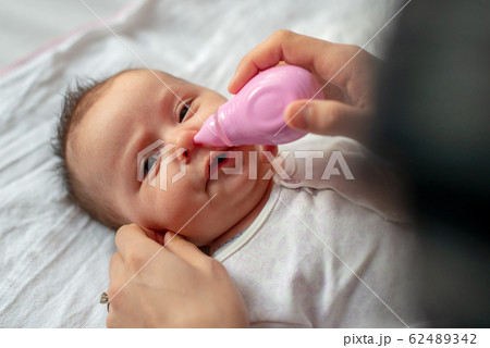 mother using baby nasal aspirator mucus nose suction 62489342