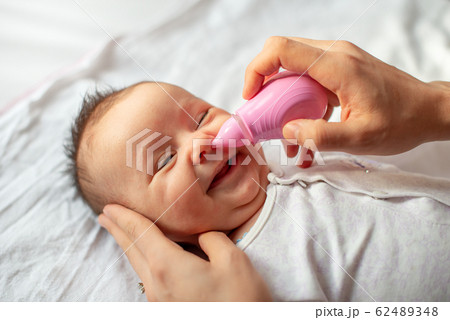 mother using baby nasal aspirator mucus nose suction 62489348