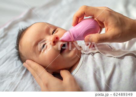 mother using baby nasal aspirator mucus nose suction 62489349