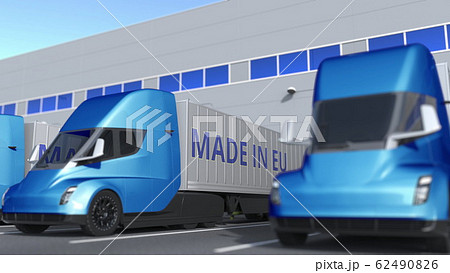 Modern semi-trailer trucks with MADE IN EU text being loaded or unloaded at warehouse. European Union business related 3D rendering Modern semi-trailer trucks with MADE IN EU text being loaded or unloaded at warehouse. European Union business related 3D rendering 62490826