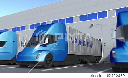 Modern semi-trailer trucks with MADE IN ITALY text being loaded or unloaded at warehouse. Italian business related 3D rendering Modern semi-trailer trucks with MADE IN ITALY text being loaded or unloaded at warehouse. Italian business related 3D rendering 62490829