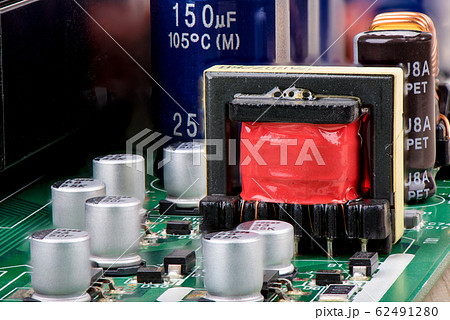 Close-up of a transformer with red isolation surrounded by capacitors. Close-up of a transformer with red isolation surrounded by capacitors. 62491280