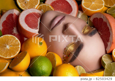 beautiful woman tall model with bright makeup lies with his eyes closed among fruits, lemon and lime. Diet and health. High end Retouch. Close up portrait beautiful woman tall model with bright makeup lies with his eyes closed among fruits, lemon and lime. Diet and health. High end Retouch. Close up portrait 62503429