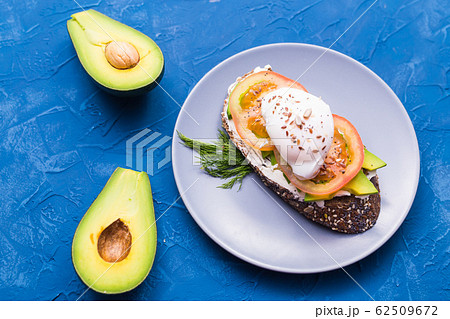 Sandwich with smoked salmon, egg and avocado on blue background, top view. Concept for healthy nutrition. Sandwich with smoked salmon, egg and avocado on blue background, top view. Concept for healthy nutrition. 62509672