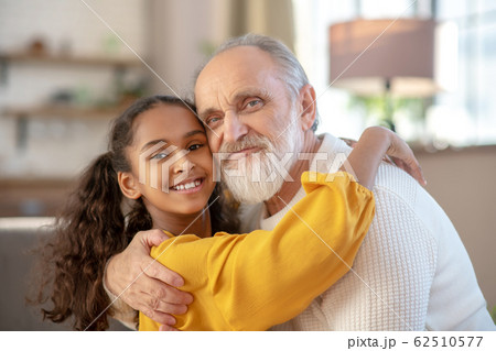 Grey-haired man and a dark-skinned girl hugging each other Grey-haired man and a dark-skinned girl hugging each other 62510577