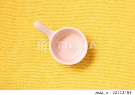 Pink ceramic bowl on yellow fabric background Pink ceramic bowl on yellow fabric background 62513463